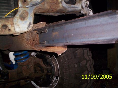 1985 Ford Bronco - This photo shows a modified vehicle frame with a new metal beam attached, along with a blue suspension spring.