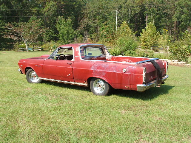 Faded red vintage Ford Ranchero pickup, rear three-quarter view on grass