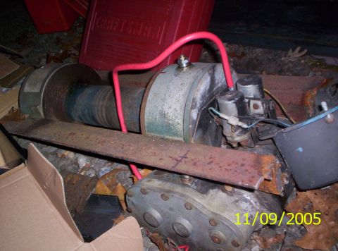 1985 Ford Bronco - A winch mechanism is shown with red hoses and electrical connections, partially obscured by debris.