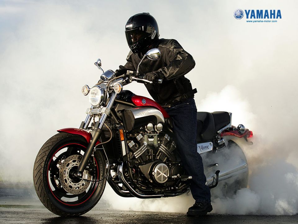 Rider doing a burnout on a red and black Yamaha V-Max motorcycle amid thick tire smoke