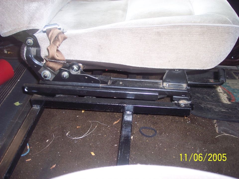 Gray cloth seat slider rails mounted to black welded tube subframe on cab floor