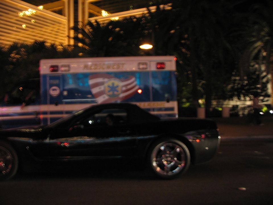 Black sports car driving past an ambulance at night