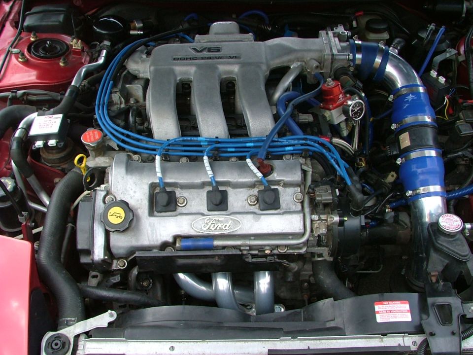 Ford DOHC V6 engine bay with blue plug wires and blue intake piping