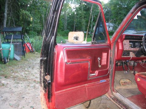 1985 Ford F-350 - Interior view of a red Ford truck, showing the driver's side door and dashboard.