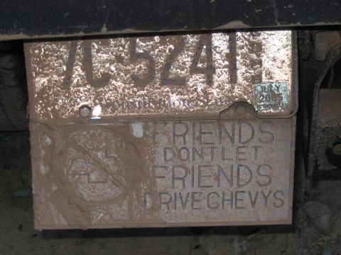 1985 Ford F-350 - A license plate frame with a humorous anti-Chevy message is covered in mud, obscuring the vehicle details.