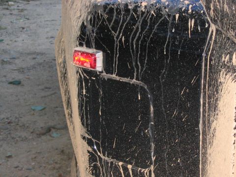 1985 Ford F-350 - Mud splatters cover the rear of a black vehicle, obscuring its details but revealing a functional tail light.