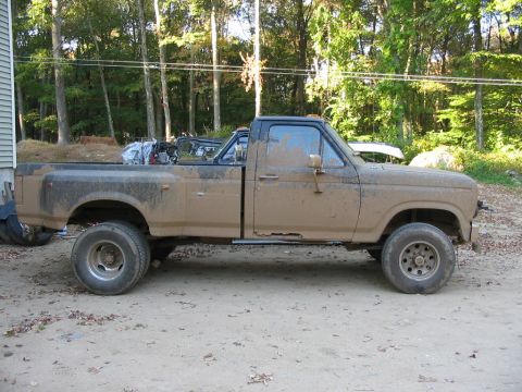 1985 Ford F-350 - This heavily soiled 1985 Ford F-350 pickup truck is shown from the side, with visible mud splatter across its body.