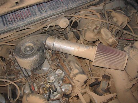 1985 Ford F-350 - Engine bay detail showing an aftermarket air intake system and filter, heavily coated in dust.