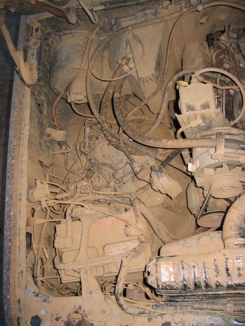1985 Ford F-350 - The engine bay is heavily soiled with mud, obscuring many details of the vehicle's components.