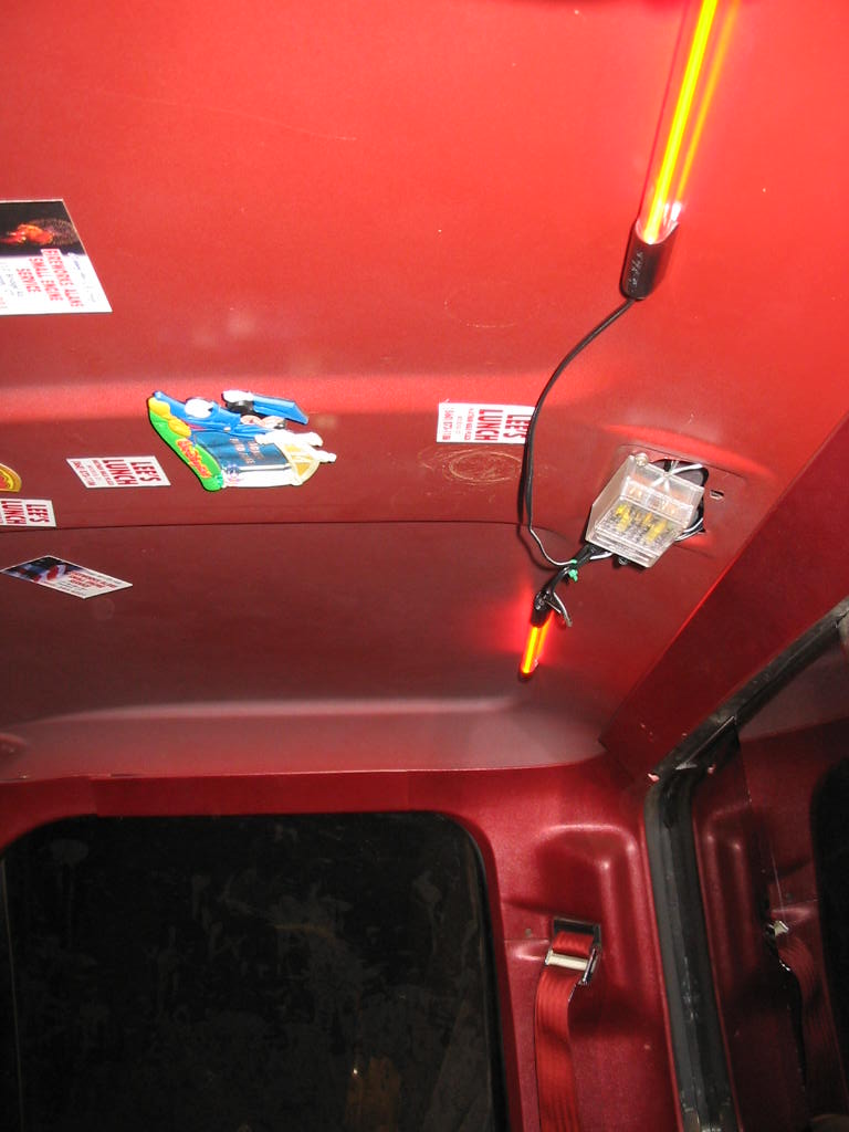 Interior roof of a red vehicle with various stickers and two yellow LED lights installed