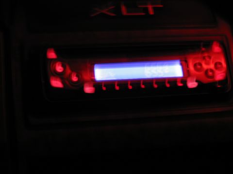 1985 Ford F-350 - The XLT badge is visible above a car stereo with a blue display and red illuminated buttons.