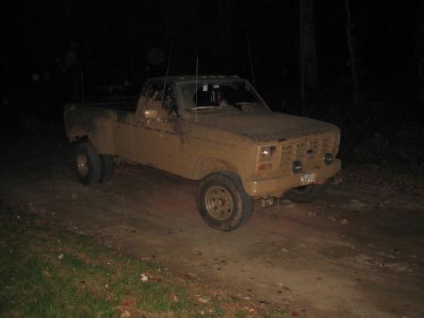 1985 Ford F-350 - Mud-covered pickup truck with dual rear wheels parked on a dirt road at night.