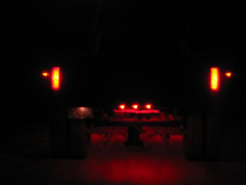 1985 Ford F-350 - The rear of a truck is visible at night, with its red brake lights and cab lights glowing.