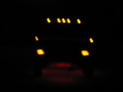 1985 Ford F-350 - A dark photo shows the front of a truck with its lights illuminated.
