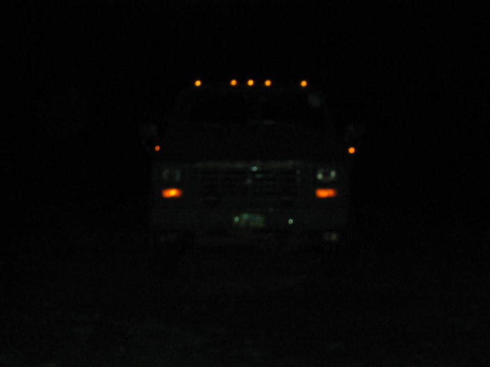 Front view of a 1985 Ford F-350 at night with roof marker lights illuminated