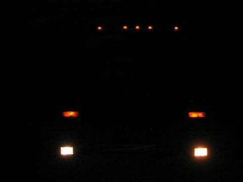 1985 Ford F-350 - The top marker lights and front turn signals of a truck are illuminated in the dark.