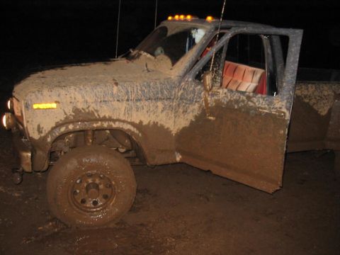 1985 Ford F-350 - Muddy pickup truck with its door ajar, seen at night in a muddy environment.