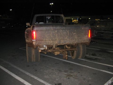 1985 Ford F-350 - This heavily soiled pickup truck, likely from the early 1980s, is viewed from the rear in a dimly lit parking lot.