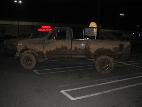 1985 Ford F-350 - Mud-covered pickup truck parked in a lot at night.