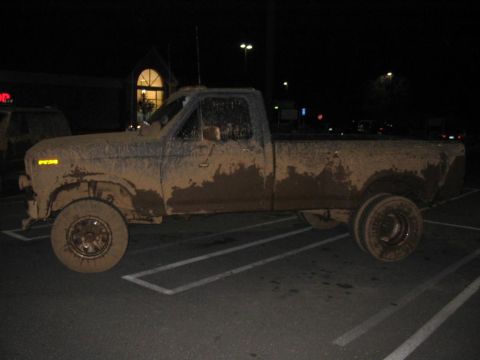 1985 Ford F-350 - This pickup truck is heavily covered in mud, suggesting recent off-road use.