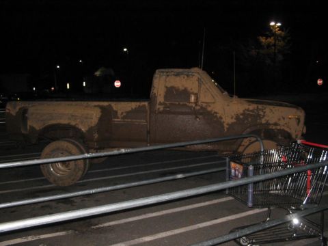 1985 Ford F-350 - A heavily mud-splattered pickup truck sits in a parking lot at night.