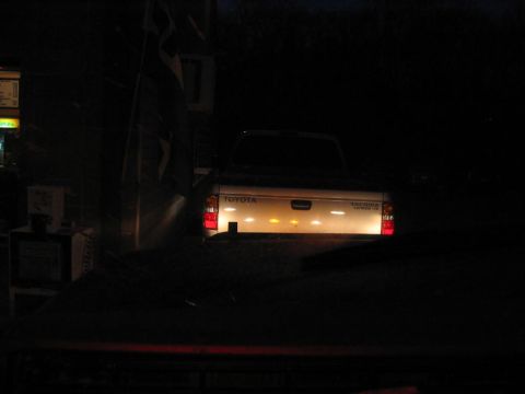 1985 Ford F-350 - Toyota Tacoma pickup truck seen from behind at night, with its taillights on.