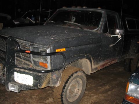 1985 Ford F-350 - Mud-covered Ford F-350 pickup truck with a brush guard and camper shell.