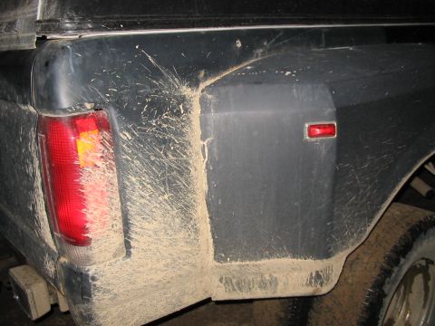 1985 Ford F-350 - Mud covers the rear side of a truck, obscuring much of its body lines and details.