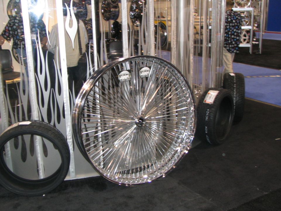 Chrome wire wheel with many spokes and two tires on display