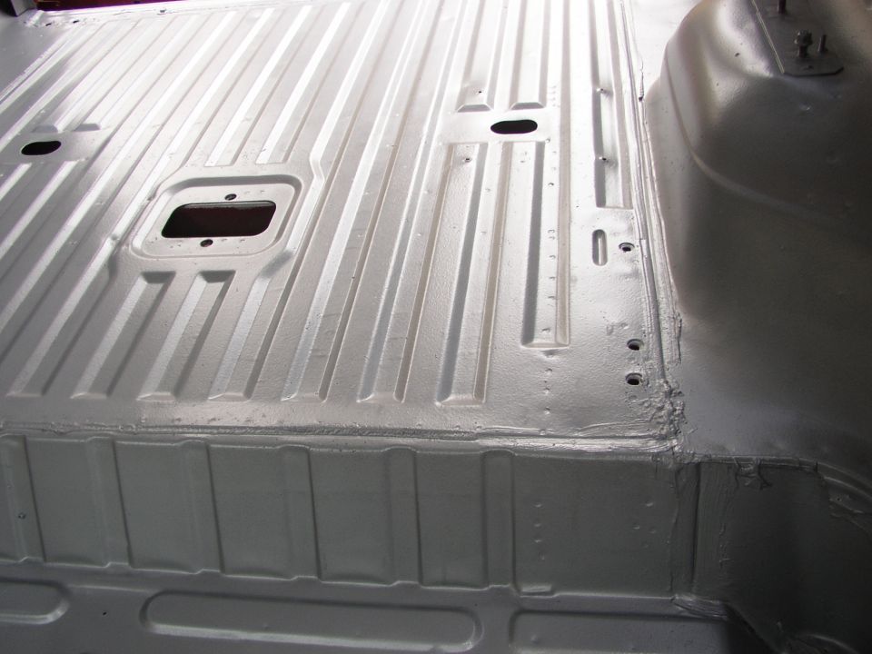 Interior floor pan of a vehicle, showing ribbed metal and some mounting holes