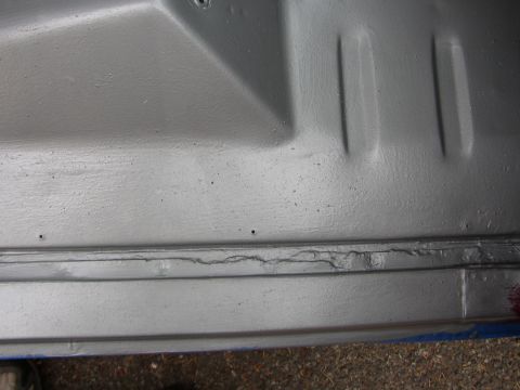 1995 Ford Bronco - Close-up of a silver painted vehicle underbody showing some cracking.