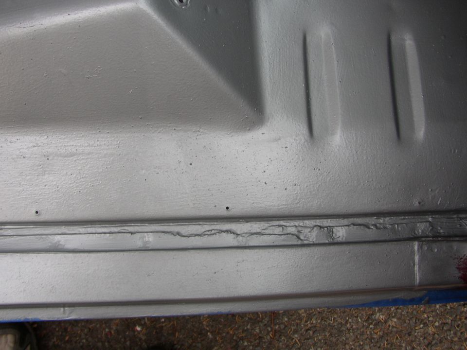 Close-up of a silver painted vehicle underbody with some cracking visible