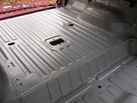 1995 Ford Bronco - The interior floor of a vehicle has been treated with a protective coating, revealing its ribbed metal structure.