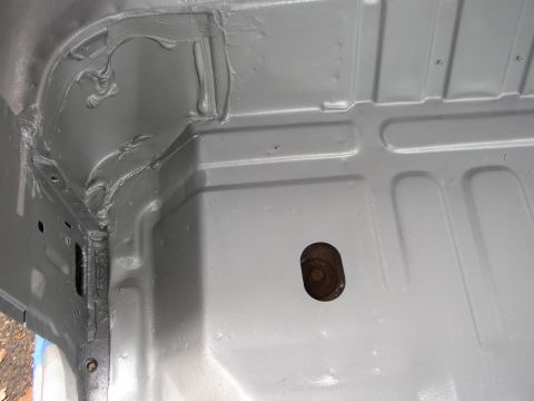 1995 Ford Bronco - The interior floor of a vehicle shows a gray coating and a hole with a bolt.