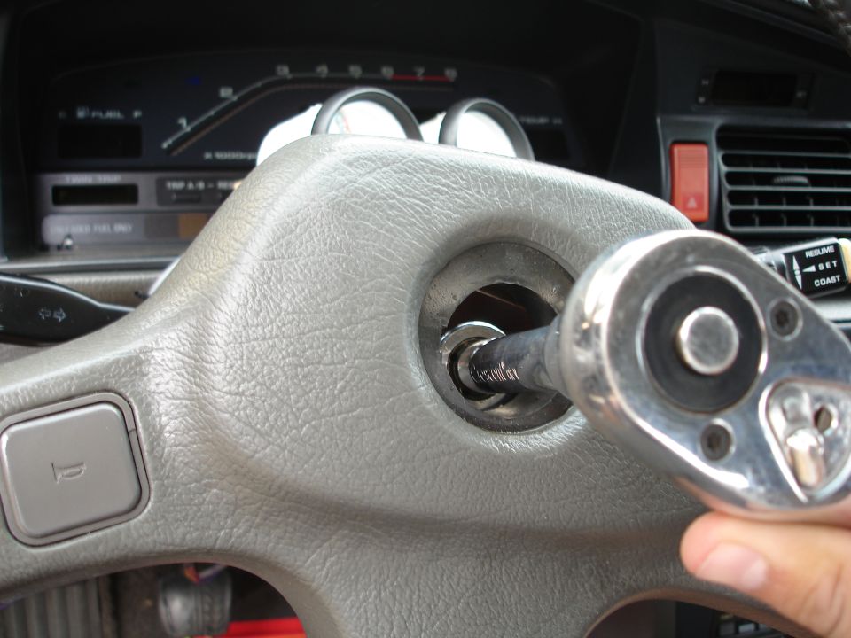 Gray steering wheel with a socket wrench in the ignition, dashboard gauges visible