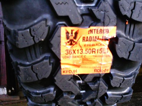 1989 Ford Bronco - Close-up of a brand-new Interco radial mud tire with the orange factory label still attached, reading 36X13.50R15, 6 PR blackwall, Load Ran…
