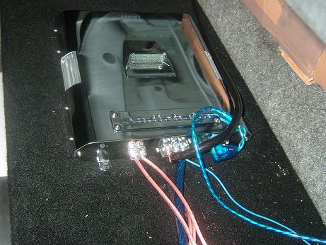 1992 Ford Crown Victoria - A car amplifier is shown with its wiring connected, installed in a carpeted area.