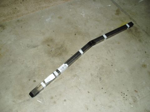 1993 Ford Taurus - A bent metal subframe part, secured with white tape, lies on a concrete floor. A barcode label is visible on the part.