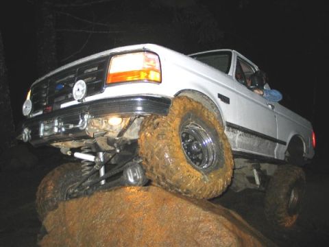 1995 Ford Bronco - Ford Bronco navigating a large rock obstacle during an off-road excursion.