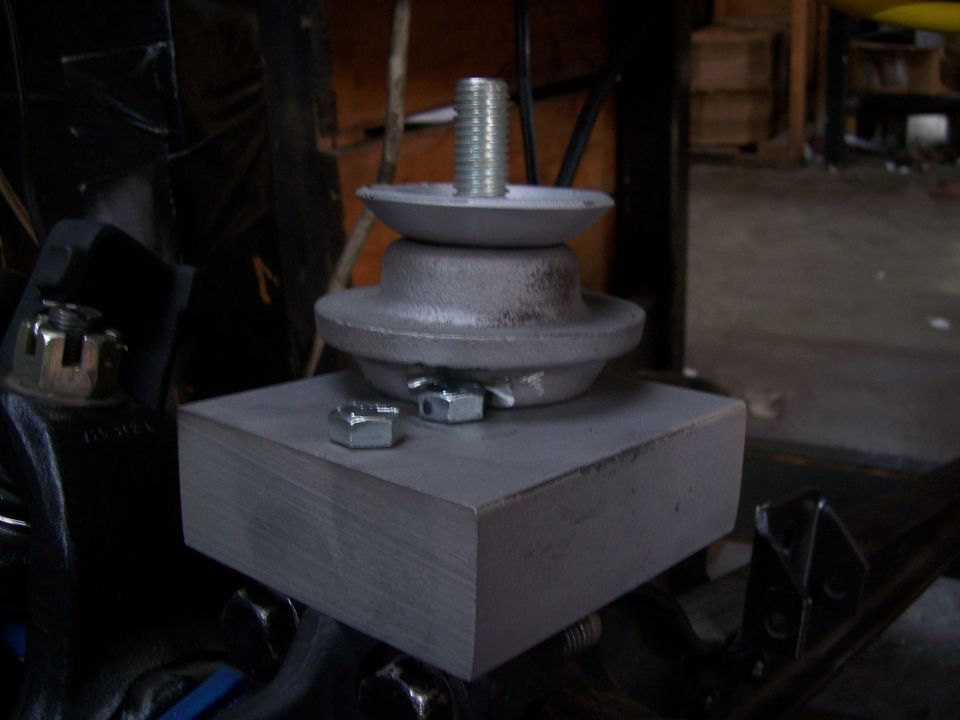 Engine mount assembly with a bolt, washer, and nuts on a metal block
