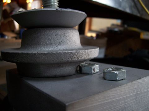 1983 Ford Bronco - Close-up of a gray metal suspension part with a bolt and nuts, likely a vehicle component.