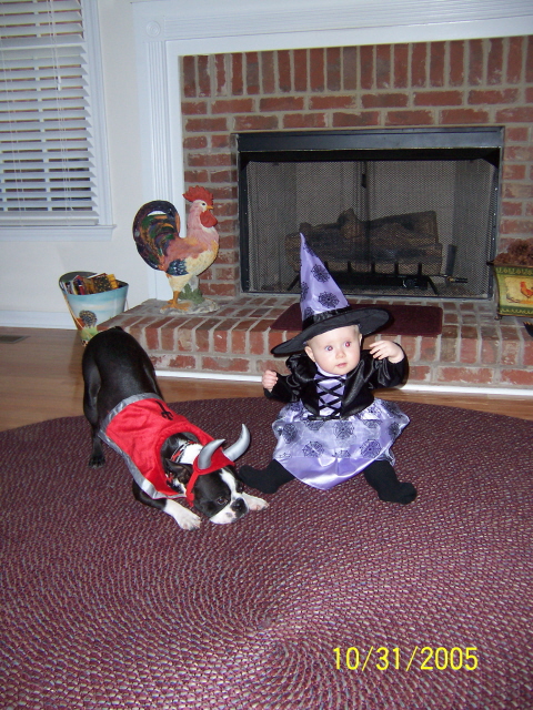 1979 Ford Bronco - A baby in a witch costume and a dog in a bull costume are on a rug in front of a fireplace.