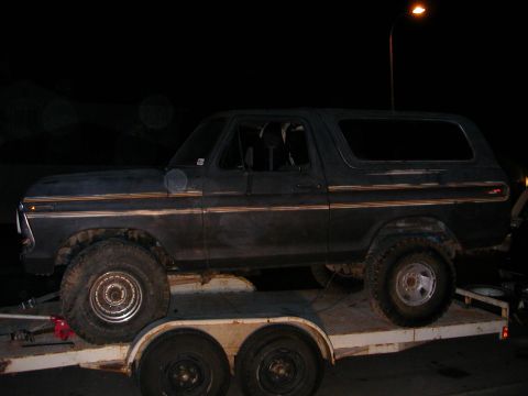 1992 Ford F-150 - A dark blue 1978 Ford Bronco is loaded onto a trailer at night, showing its side profile with gold trim details.