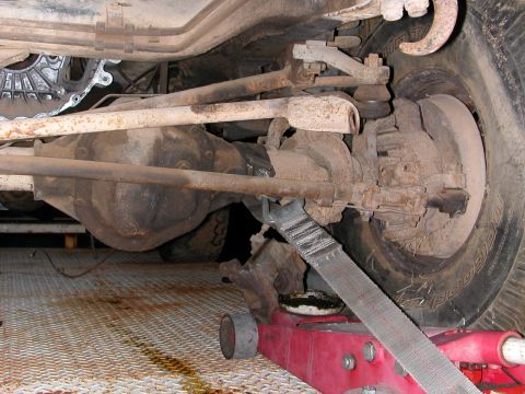 1992 Ford F-150 - Close-up view of a vehicle's undercarriage, showing suspension components and the differential, supported by a red jack.