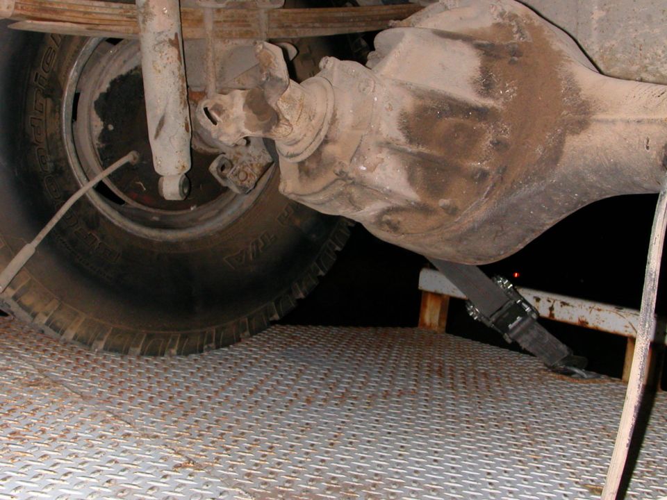 Close-up of a truck's rear axle, differential, leaf spring, and shock absorber