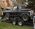 1978 Ford Bronco - A black 1978 Ford Bronco is loaded onto a trailer in a residential setting.