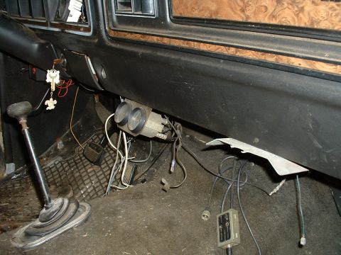 1978 Ford Bronco - The interior of a vehicle shows a floor shifter, dashboard, and aftermarket gauges, with visible wiring and floor mats.