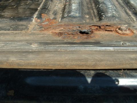 1978 Ford Bronco - Close-up of a heavily rusted truck bed, showing a hole and a bolt.