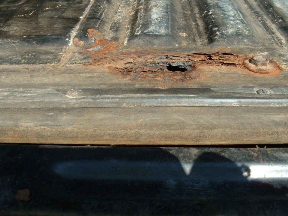 Rusted truck bed with hole and bolt