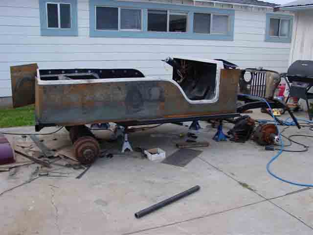 Jeep CJ body and frame disassembled on jack stands in a driveway